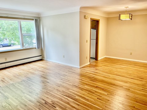 A room with wooden flooring and a window overlooking a street.
